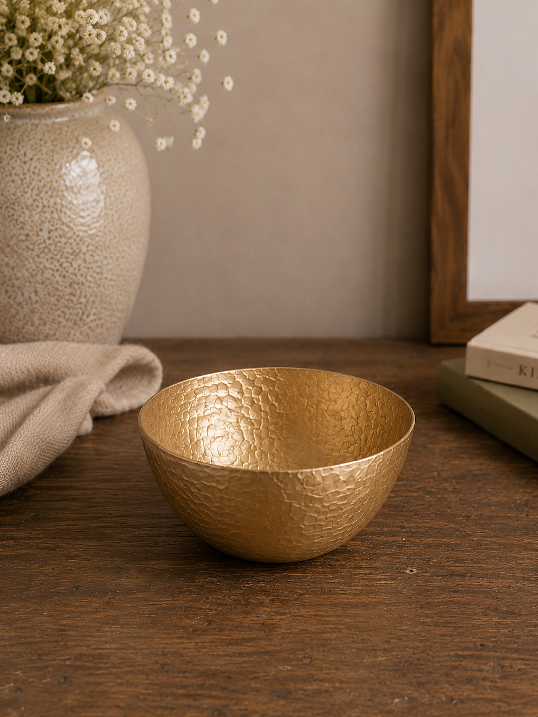 Goldene Dekoschale Sanna aus Metall mit strukturierter Oberfläche auf einem Holztisch.