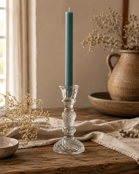 Frostgrüne Flachkopf-Stabkerze im dekorativen Glas-Kerzenhalter Liv auf rustikalem Holztisch im warmen Farmhouse-Stil.