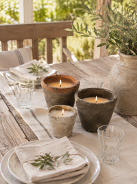 Rustikale Outdoor-Kerzen Terra auf einem hell gedeckten Holztisch im natürlichen Farmhouse-Stil